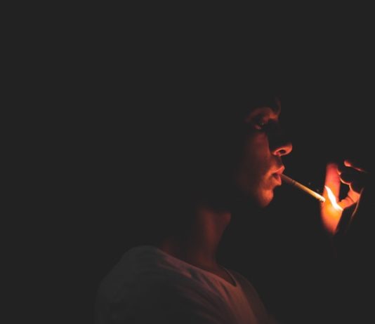 Jeune homme allumant sa cigarette dans le noir avec un briquet