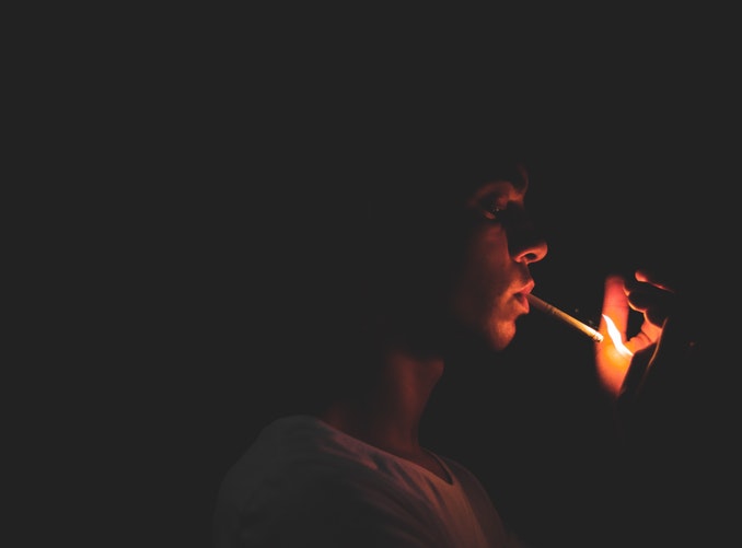 Jeune homme allumant sa cigarette dans le noir avec un briquet