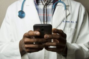 Un médecin noir manipulant un smartphone.