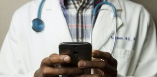 Un médecin noir manipulant un smartphone.