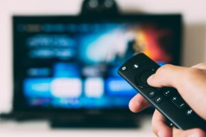 Une personne tenant une commande devant sa télé.